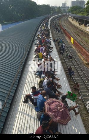 Dhaka. 8th July, 2022. Travelers sitting on the roof of a train leave a station in Dhaka, Bangladesh, July 7, 2022. As Eid al-Adha festival approaches, many people from Bangladesh capital Dhaka have streamed out of the city to join the festival with their kith and kin in village homes. Credit: Xinhua/Alamy Live News Stock Photo