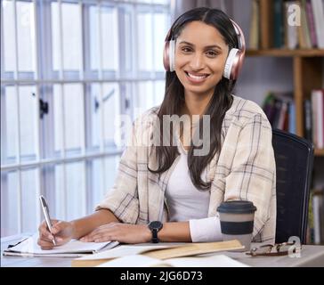 Happily putting in the hours. Shot of a young student doing her homework at the kitchen table. Stock Photo