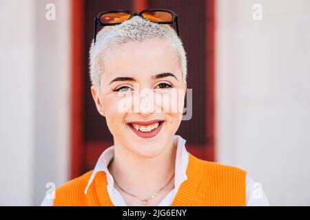 Happy Blonde Young Girl Looking at Camera. Close Up Portrait of woman laughing and smiling outdoors Stock Photo