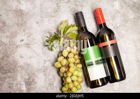 White wine and red wine bottle with bunch of grapes, on a marble background, top view. Stock Photo