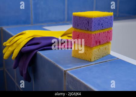 Rubber gloves and sponges inside bathroom. Closeup. Set of colorful accessory for house cleaning. Clean house. Front view. Stock Photo