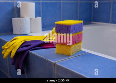 Rubber gloves and sponges inside bathroom. Closeup. Set of colorful accessory for house cleaning. Clean house. Front view. Stock Photo