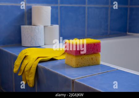 Rubber gloves and sponges inside bathroom. Closeup. Set of colorful accessory for house cleaning. Clean house. Front view. Stock Photo