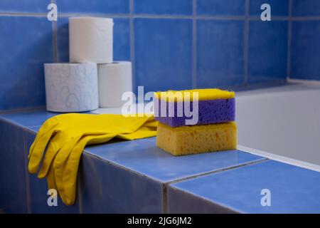 Rubber gloves and sponges inside bathroom. Closeup. Set of colorful accessory for house cleaning. Clean house. Front view. Stock Photo