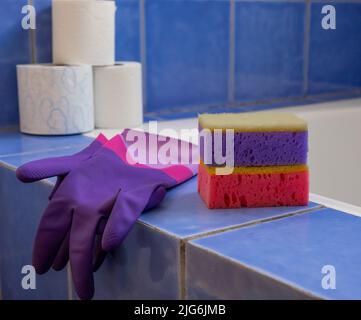 Rubber gloves and sponges inside bathroom. Closeup. Set of colorful accessory for house cleaning. Clean house. Front view. Stock Photo
