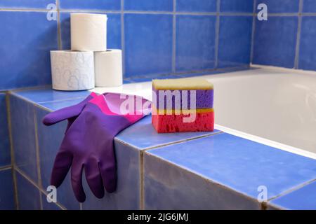 Rubber gloves and sponges inside bathroom. Closeup. Set of colorful accessory for house cleaning. Clean house. Front view. Stock Photo