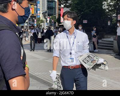 Tokyo, Japan. 8th July, 2022. A staff member distributes copies of an extra edition of the Yomiuri Shimbun newspaper reporting on the shooting of former Japanese Prime Minister Shinzo Abe, on a street in Tokyo, Japan, July 8, 2022. Credit: Sun Jialin/Xinhua/Alamy Live News Stock Photo
