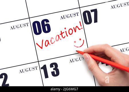 6th day of August. A hand writing a VACATION text and drawing a smiling face on a calendar date 6 August. Vacation planning concept. Summer month, day Stock Photo