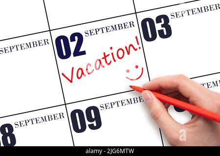 2nd day of September. A hand writing a VACATION text and drawing a smiling face on a calendar date 2 September . Vacation planning concept. Autumn mon Stock Photo