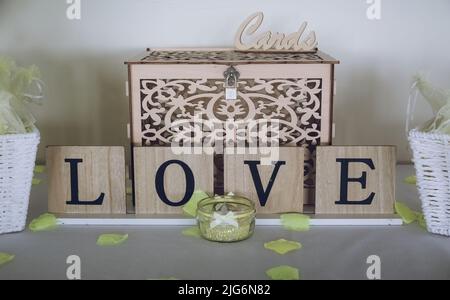 A sign reading love on a table at a wedding reception in front of a wedding card collection box Stock Photo