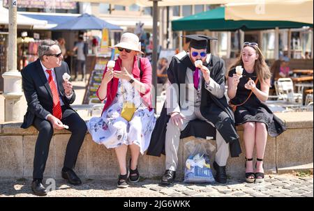 Brighton, UK. 8th July, 2022. A University of Sussex student and family enjoy an ice cream on Brighton seafront in beautiful hot sunshine after their graduation ceremony . A possible heatwave is forecast for parts of the UK over the next week . : Credit Simon Dack/Alamy Live News Stock Photo