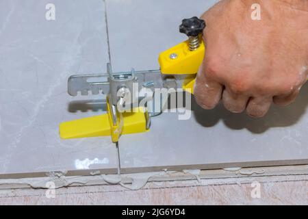 Working on tile leveling with plastic clips and wedges in a bathroom Stock Photo