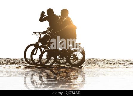 positive family rides bicycles on beach Stock Photo