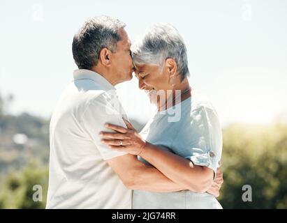 A kiss speaks a thousand words. Shot of senior couple spending time together in nature. Stock Photo