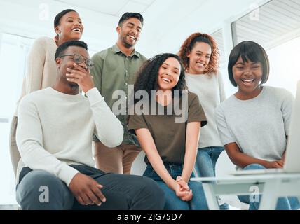 Some of these videos are really funny. Shot of a diverse group of people using a laptop during group therapy. Stock Photo