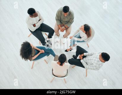 Group therapy is a must. High angle shot of an unrecognisable group of people sitting together and talking during therapy. Stock Photo