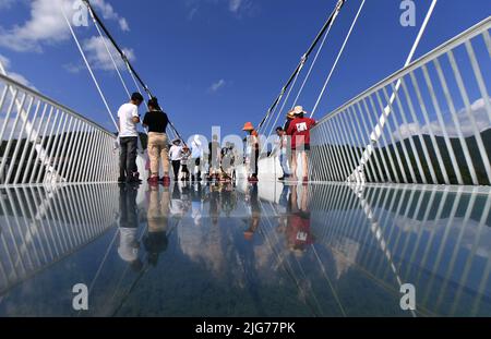 Zhangjiajie, China's Hunan Province. 8th July, 2022. Tourists walk on a glass-bottomed bridge at Zhangjiajie Grand Canyon, central China's Hunan Province, July 8, 2022. As the summer vacation approaches, Zhangjiajie, a popular tourist destination in Hunan Province, has taken a series of measures to boost the recovery of tourism. Credit: Zhao Zhongzhi/Xinhua/Alamy Live News Stock Photo