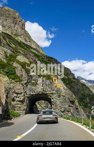 Supercar sports car Porsche GT3 driving tunnel carved in rock, above painted geographical marking coat of arms of canton Uri, Wassen, canton Uri Stock Photo
