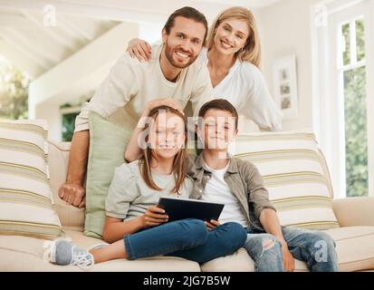Expanding our minds together. Shot of a young caucasian family spending time together at home while using a digital tablet. Stock Photo