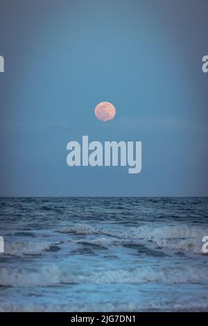 Detailed full moon over dark waves of the Atlantic Ocean on a clear night. Stock Photo