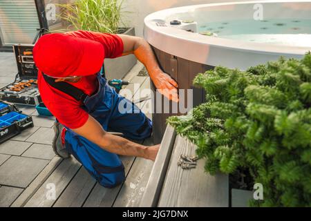Garden Outdoor Hot Tub Maintenance Performed by Professional Caucasian Technician in HIs 40s. SPA Repairing. Stock Photo