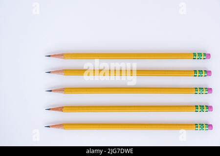 Negative space is utilized with five sharp pencils lined up on a white sheet of paper pointing to the left. Stock Photo