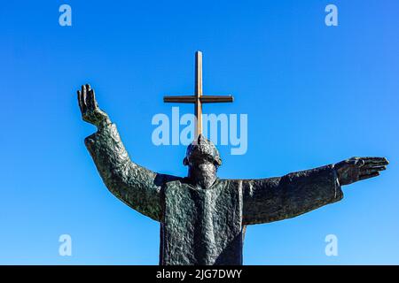 The Great Cross stands behind the bronze statue of Father Lopez looking heavenward in St. Augustine, Florida. Stock Photo