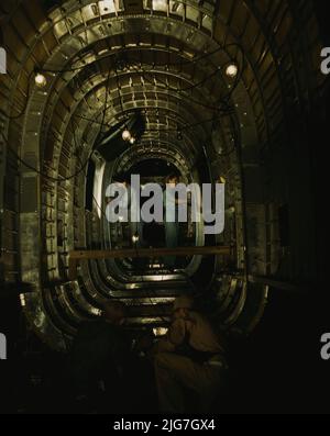 Installing structural parts of a C-87 transport plane in the tunnel of a tail fuselage section at the Consolidated Aircraft Corporation plant, Fort Worth, Texas. Stock Photo