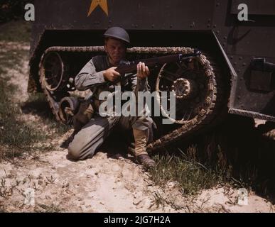 A young soldier of the armored forces holds and sights his Garand rifle like an old timer, Fort Knox, Ky. He likes the piece for its fine firing qualities and its rugged, dependable mechanism. Infantryman with halftrack. Stock Photo