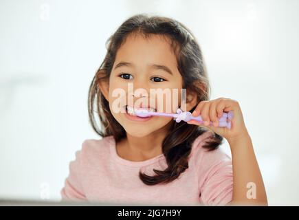 She knows how to brush well. Shot of an adorable little girl brushing her teeth in a bathroom at home. Stock Photo