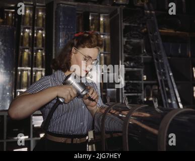 Operating a hand drill at the North American Aviation, Inc., [a] woman is in the control surface department assembling a section of the leading edge for the horizontal stabilizer of a plane. Stock Photo