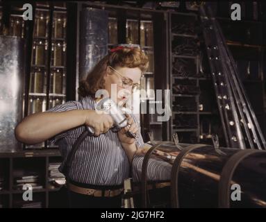 Operating a hand drill at North American Aviation, Inc., [a] woman is working in the control surface department assembling a section of the leading edge for the horizontal stabilizer of a plane, Inglewood, Calif. Stock Photo