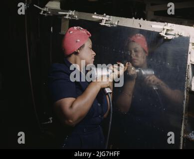 Operating a hand drill at Vultee-Nashville, woman is working on a &quot;Vengeance&quot; dive bomber, Tennessee. The tool in the image might be a rivet gun, rather than a hand drill as stated in the caption. Stock Photo