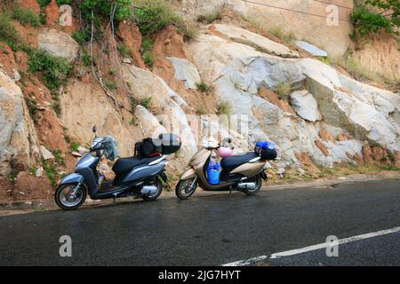 Phan Thiet City, Binh Thuan Province, Vietnam - January 2, 2015: Two motorbikes stop on the road beside a cliff in the sunset light Stock Photo