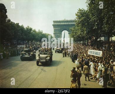 Crowds of French patriots line the Champs Elysees to view Allied tanks and half tracks pass through the Arc du Triomphe, after Paris was liberated on August 25, 1944. Showing Free French tanks and half tracks of General Leclerc's 2nd Armored Division passing through the Arc du Triomphe in Paris, probably on August 26, 1944. Sign at left &quot;De Gaulle au pouvoir&quot; and sign at right &quot;Vive De Gaulle.&quot; . Stock Photo