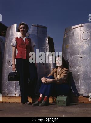 Two assembly line workers at the Long Beach, Calif., plant of Douglas Aircraft Company enjoy a well-earned lunch period, Long Beach, Calif. Nacelle parts of a heavy bomber form the background. Stock Photo