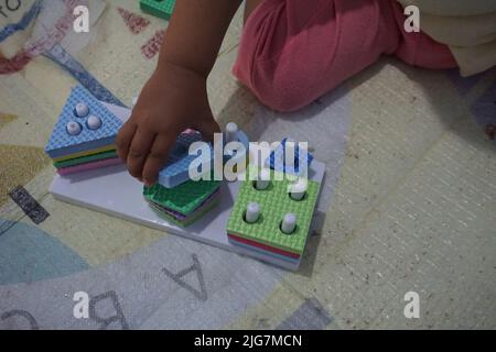 Child's hand, playing with montessory toys. Geometry puzzle. education for children that seeks to develop natural interests and activities. Stock Photo