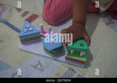 Child's hand, playing with montessory toys. Geometry puzzle. education for children that seeks to develop natural interests and activities. Stock Photo
