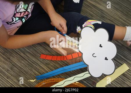 little child girl cutting a rainbow paper. kids rainbow arts and crafts. Stock Photo