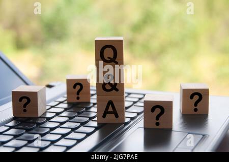 Question and answer text on wooden block on top of laptop with blurred nature background. Question and answer concept Stock Photo