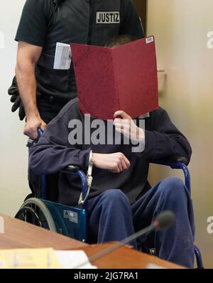 Cologne, Germany. 08th July, 2022. Handcuffed to a wheelchair, a 29-year-old man is pushed into a courtroom at the Cologne Regional Court by a court official. He is said to have fatally injured his parents with an axe. After the crime, he jumped from a highway bridge and seriously injured himself. (to 'Parents surprised with axe blows - son on trial for attempted murder') Credit: Gregor Bauernfeind/dpa/Alamy Live News Stock Photo
