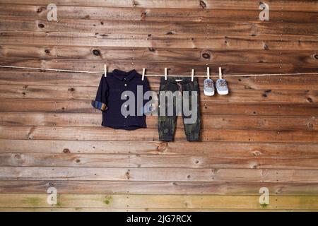 Children's fashion - set of children's clothing, long-sleeve shirt, jeans and shoes; Photo on wooden background. Stock Photo