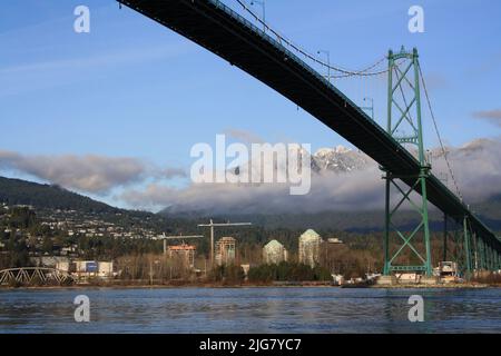 a low angle shot of Lions Gates Bridge in the background of mountains in Vancouver, British Columbia, Canada Stock Photo