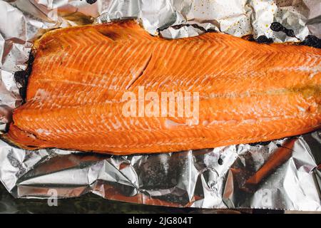 whole cooked, barbecued Copper River Salmon fillet on foil on the grill Stock Photo