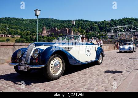 Heidelberg, Germany. 08th July, 2022. Vintage cars drive across the Old Bridge as part of the 'ADAC Heidelberg Historic'. During the event, 180 classic cars will tour the Odenwald, Kraichgau, Enzkreis and the northern district of Karlsruhe. Credit: Uwe Anspach/dpa/Alamy Live News Stock Photo