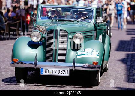 Heidelberg, Germany. 08th July, 2022. A classic car drives across the market square as part of the 'ADAC Heidelberg Historic'. During this event, 180 classic cars tour the Odenwald, Kraichgau, Enzkreis and the northern district of Karlsruhe. Credit: Uwe Anspach/dpa/Alamy Live News Stock Photo