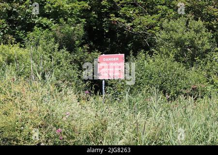 A warning sign to keep away from the cliff at Axmouth on the Jurassic coast. Rain and erosion causes frequent rock falls Stock Photo