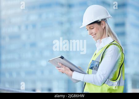 Visualizing everything springing up around me. Shot of a young female contractor using her digital tablet on site. Stock Photo