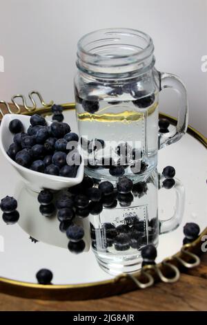 Water, lemonade flavored with fresh berries, mirror tray, bowl, decoration Stock Photo