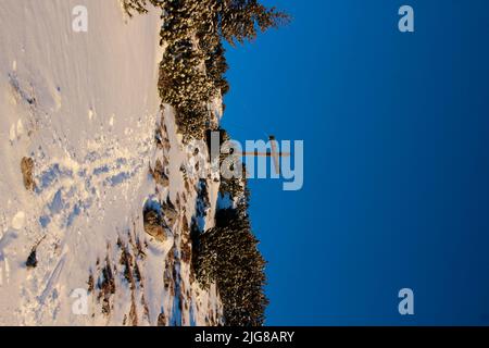 Winter hike, ski tour to Simetsberg. Germany, Bavaria, Walchensee, Einsiedl, summit cross at 1840m, tracks in the snow Stock Photo